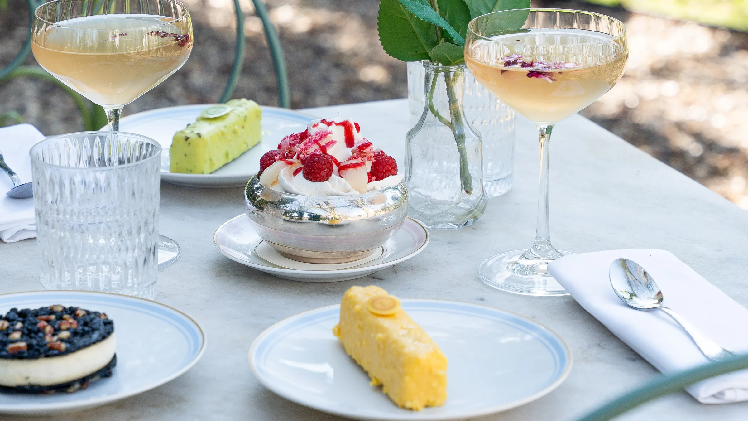 Une table dressée au jardin : coupes, pâtisseries et dessert aux framboises